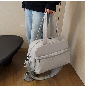 Close-up of light grey large capacity nylon travel bag with adjustable padded shoulder strap