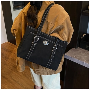 Détail du sac cabas noir avec fermoir rotatif argenté et surpiqûres blanches contrastées