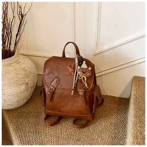 Brown faux leather backpack with vintage flap and cute plush bear charm detail