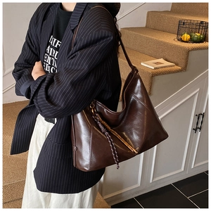 Détail du sac cabas en cuir marron foncé montrant la structure hobo et le charme