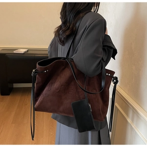 Dettaglio laterale della borsa tote in pelle scamosciata marrone sulla modella