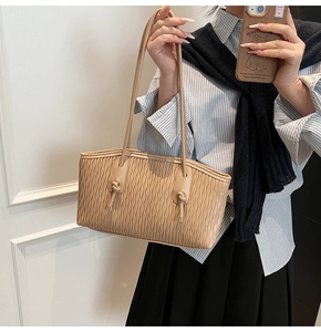 Détail du sac beige avec une texture plissée ondulée et des anses à nœuds élégants