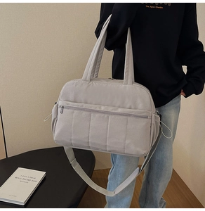 Detail of light grey quilted travel bag with adjustable strap and durable fabric texture