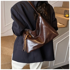Détail du grand sac cabas marron foncé avec charm étoile et texture cuir ciré poli