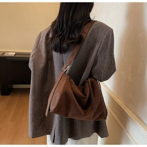 Detail of deep brown suede hobo bag showing soft texture and metal buckle on strap