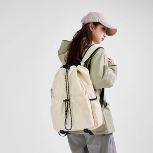 Detailed view of cream nylon drawstring backpack with ripstop texture and black straps
