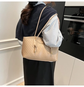 Détail d'un sac à bandoulière plissé beige avec texture ondulée et finitions dorées