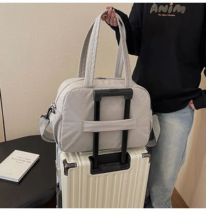 Detail of grey travel bag featuring luggage strap on back for suitcase attachment