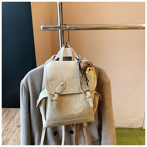 Detail of cream-white vintage backpack with pleated PU leather and small bear charm