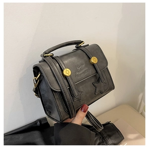 Detail of vintage black oil-wax crossbody bag with gold hardware and star patch