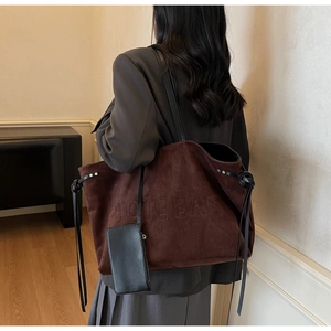 Dettaglio della borsa tote in pelle scamosciata marrone scuro con scritta in rilievo e nappe
