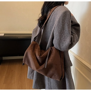 Detail of dark brown suede tote bag featuring a wide shoulder strap and metal buckle