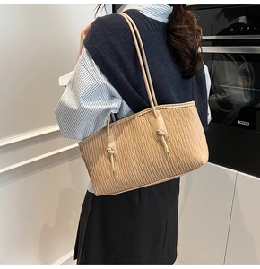 Détail du sac cabas beige avec texture plissée ondulée et finitions de nœuds dorés