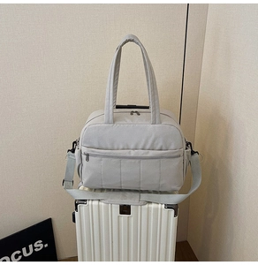 Detail of light gray nylon travel bag featuring quilted design and adjustable shoulder strap