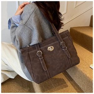 Close-up of a large coffee-colored vintage tote bag with white stitching and silver clasp