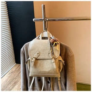 Close-up of cream faux leather backpack with retro flap, buckle and cute bear charm