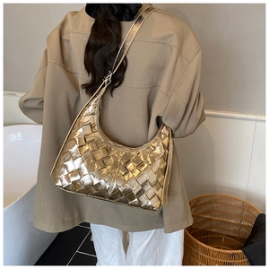 Detail einer metallisch goldenen geflochtenen Hobo-Tasche mit Textur und Trageriemen