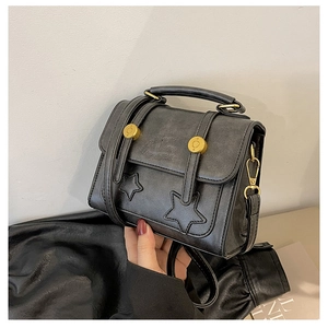 Detailed shot of retro black crossbody bag featuring stitched star patterns and gold hardware