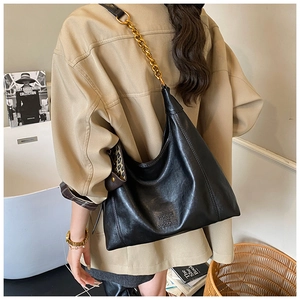 Detailansicht einer großen schwarzen Hobo-Tasche aus Leder mit goldener Kette an der Schulter