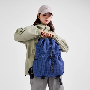 Detail showing blue checkered texture and large front zipper pocket on drawstring backpack