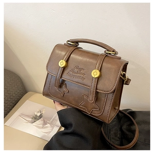Detail of brown vintage PU leather bag with star studs and embossed fashion text