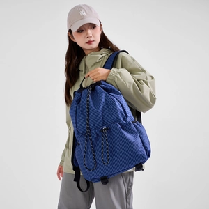 Detail of blue grid drawstring backpack showing side elastic pocket and water-repellent nylon