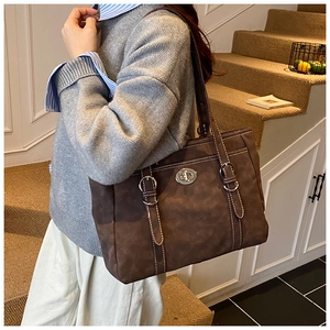 Detail view of a large dark brown matte leather tote bag with stylish metal turn-lock closure