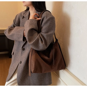 Detail of soft brown suede tote bag with decorative straps and leather shoulder handle