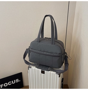 Detail of dark grey travel bag on a suitcase showing durable nylon and shoulder strap