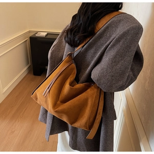 Rear view of a model wearing a large brown suede tote bag with a wide shoulder strap