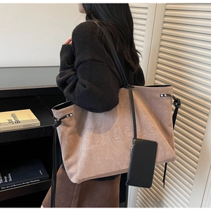 Dettaglio della borsa tote in pelle scamosciata marrone con scritte in rilievo e astuccio