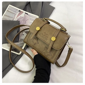 Detail of a brown leather shoulder bag with star patches and adjustable strap on a studio set