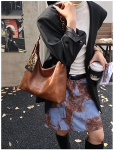 Detail der karamellbraunen Hobo-Tasche mit Ledertextur und Leopardenmuster-Anhänger