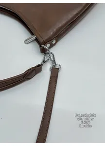 Detail of silver detachable metal buckle and hardware on dark brown leather shoulder bag