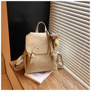 Detail of beige faux leather backpack with vintage buckle and brown plush bear charm