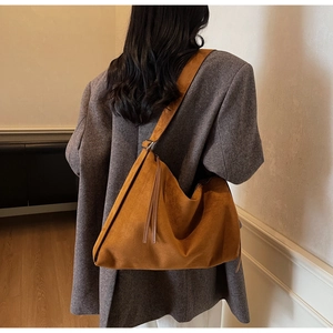 Detail view of ginger suede tote bag with long tassel fringe and wide shoulder strap