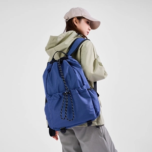 Detail view of blue checkered drawstring backpack with side pockets on model