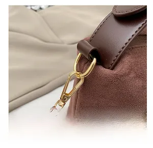 Detail of high-quality golden metal hook and dark brown leather strap on suede pillow bag