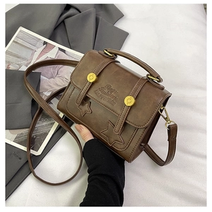 Close-up of retro brown messenger bag with star patches and embossed fashion text
