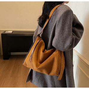 Detailed close-up of brown suede tote bag featuring side tassels and a soft matte finish