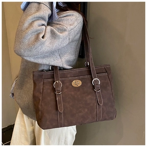 Detail of vintage brown tote bag with white contrast stitching and silver metal turn-lock