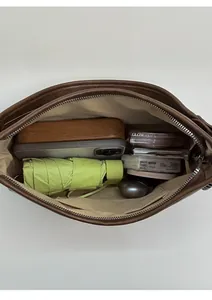 Top-down view of spacious brown leather bag interior with umbrella, phone and essentials