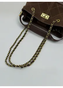 Detail of chocolate suede bucket bag showing quilted texture and gold chain strap