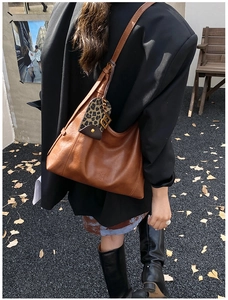 Nahaufnahme der braunen Hobo-Tasche aus Leder mit Leoparden-Anhänger und Logo-Prägung