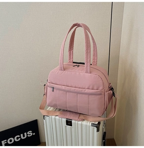 Pink waterproof travel bag on suitcase with wide handles and adjustable strap