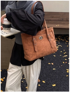 Close-up of brown suede tote bag with metal twist-lock fastener and double shoulder straps
