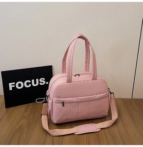 Detail of light pink nylon travel bag featuring reinforced handles and adjustable strap
