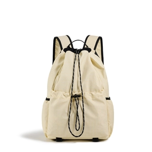 Macro view of beige drawstring backpack showing micro-check ripstop fabric texture