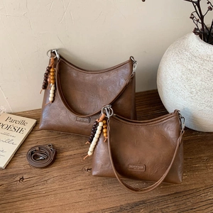 Detail of two vintage brown PU leather handbags with wooden bead charms and long straps