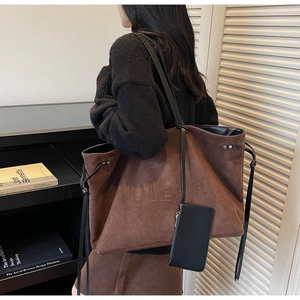 Dettaglio della borsa tote in pelle scamosciata marrone con logo e tracolla nera